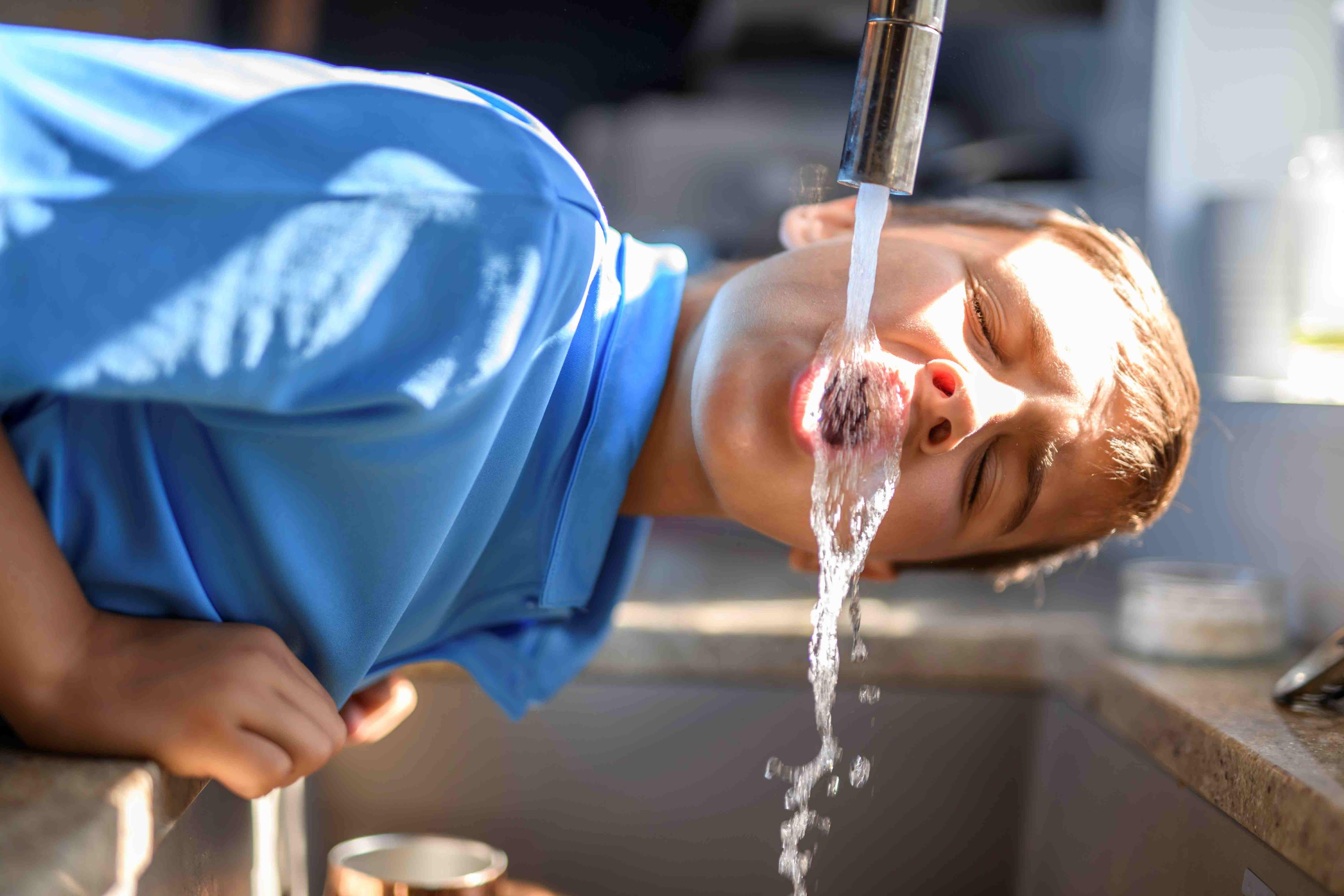 Kid drinking from kitchen faucet